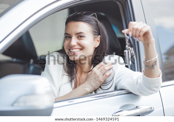Young attractive woman just bought a new
car. female holding keys from new
automobile.