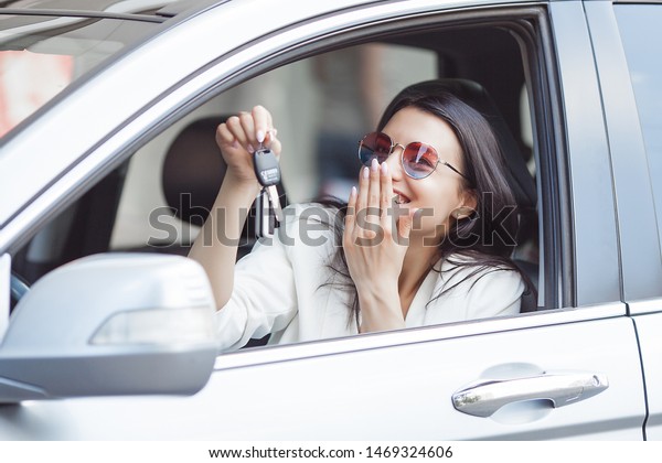 Young attractive woman just bought a new\
car. female holding keys from new\
automobile.