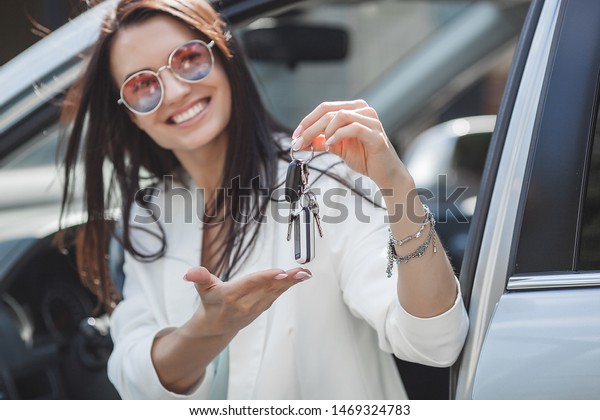 Young attractive woman just bought a new
car. female holding keys from new
automobile.