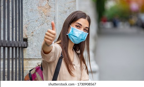 Young Attractive Woman With Mask And Gloves Showing Thumbs Up. Coronavirus Pandemic Alert. Covid-19. Beautiful Caucasian Young Woman With Disposable Face Mask