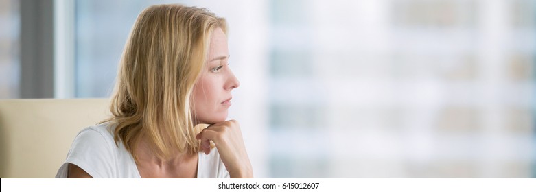 Young attractive woman at a modern office desk, working with laptop, looking at the window, thinking about a post. Horizontal photo banner for website header design with copy space for text 