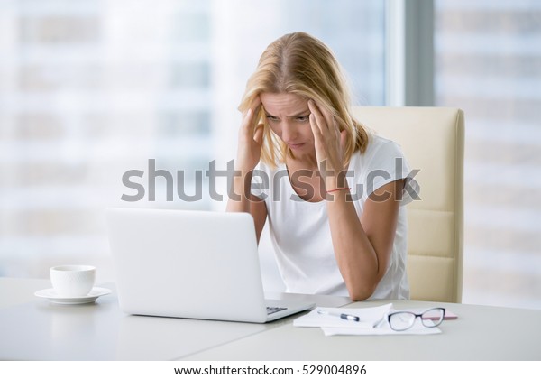 Young attractive woman at modern office desk,\
working on laptop, massaging temples to forget about constant\
headaches, noisy loud office giving a migraine, relieving stress,\
chronic pain, help soothe