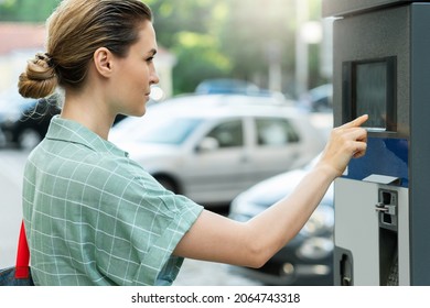 Young attractive woman paying in the parking meter machine 