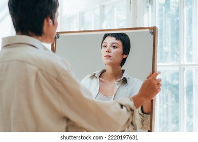 A young attractive woman peers at her reflection in the mirror. - Powered by Shutterstock