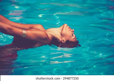 young attractive woman in  in pool with head thrown back side view
