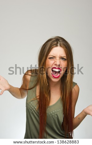 Young attractive woman posing with crazy expression on white background