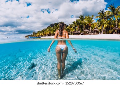 Young attractive woman posing in transparent blue ocean. Swimming in blue water at Mauritius