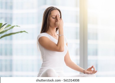 Young Attractive Woman Practicing Yoga Exercise, Sitting In Sukhasana Pose, Performing Alternate Nostril Breathing Technique, Nadi Shodhana Pranayama, Working Out, Wearing White Sportswear, Indoor 