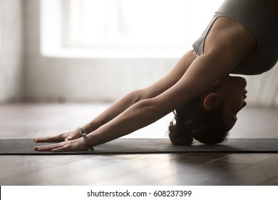 Young Attractive Woman Practicing Yoga, Standing In Downward Facing Dog Exercise, Adho Mukha Svanasana Pose, Working Out, Wearing Sportswear Bra, White Loft Studio Background, Close Up