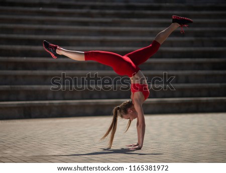 Young attractive woman practicing yoga outdoors. The girl performs a handstand upside down. Sports, yoga, fitness and health concept