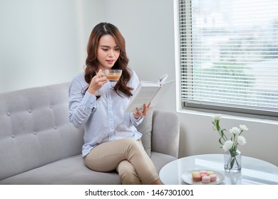 Young attractive woman read book and drink coffee sitting near window at home - Shutterstock ID 1467301001