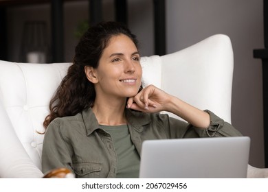 Young Attractive Woman Resting In Cozy Leather Armchair With Laptop Looking Into Distance Daydreaming, Enjoy Carefree Day Off With Modern Tech, Consider Purchase On Internet Relaxing Alone At Home