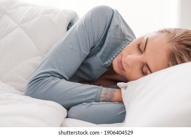 Junge attraktive Frau schlafend im Schlafzimmer, sie liegt auf der Seite und entspannt mit geschlossenen Augen geschlossen