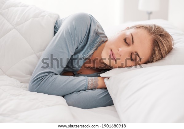 Young attractive woman\
sleeping in the bedroom, she is lying on the side and relaxing with\
eyes closed