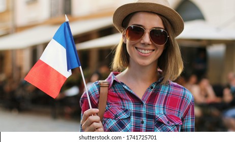 Young Attractive Woman With Sunglasses In Stylish Hat Waving French Flag On The Centre Of City. Flag Of France