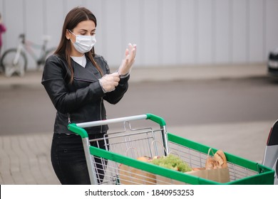 A young attractive woman taking groceries from a supermarket from the trolley to car truck. Social distancing for protection, face mask, disposable gloves to prevent infection. Food shopping during - Powered by Shutterstock