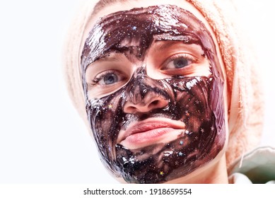 Young attractive woman with a towel on her head and a moisturizing mask on her face close-up on a white background, copy space