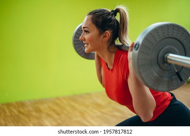 Young attractive woman training with the barbell in the gym