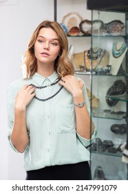 Young Attractive Woman Trying On Elegant Necklace Of Black Tahitian Pearls In Jewelry Store