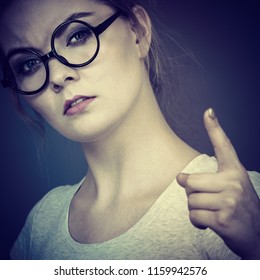 Young Attractive Woman Wearing Eyeglasses Pointing Into Camera, Teenage Judging Someone. Studio Shot On Grey Background.