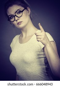 Young Attractive Woman Wearing Eyeglasses Pointing Into Camera, Teenage Judging Someone. Studio Shot On Grey Background.