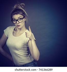 Young Attractive Woman Wearing Eyeglasses Pointing Into Camera, Teenage Judging Someone. Studio Shot On Grey Background.