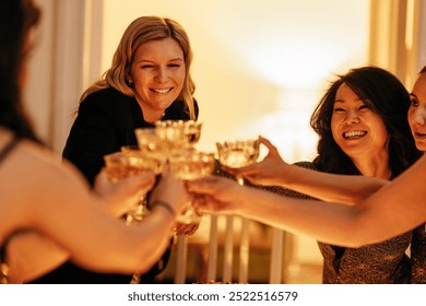 Young attractive women clink glasses of champagne. Charming multiethnic female friends in fancy dresses raise a toast at a bachelorette party. A fun party at home in the living room. - Powered by Shutterstock