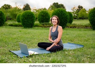 Young Attractive Women Sitting At Yoga Class On Fitness Mat While Watching Fitness Videos Using Laptop During Video Training. Concept Of Online Classes, Education Distant App, High Quality Photo.