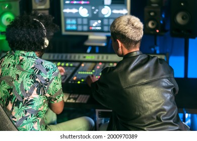 Young audio engineer people having fun working with mixer sound panel control in music recording studio