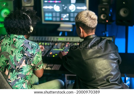 Young audio engineer people having fun working with mixer sound panel control in music recording studio