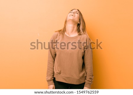 Young authentic charismatic real people woman against a wall relaxed and happy laughing, neck stretched showing teeth.