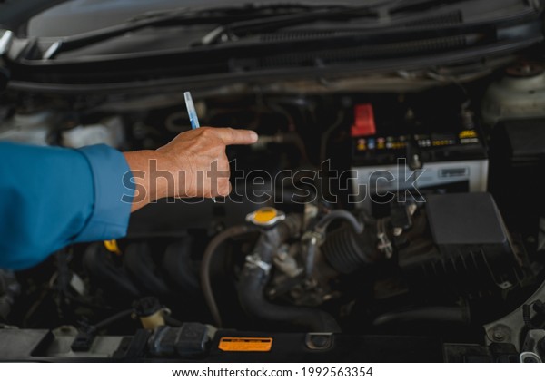 Young auto mechanic checking the engine. He\
pointed at the engine with his\
hand.