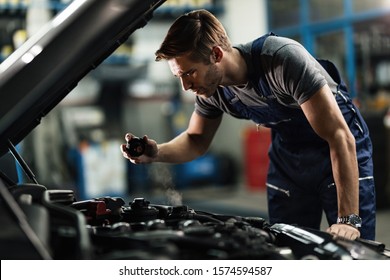 Young Auto Mechanic Checking Overheated Car Coolant System In Auto Repair Shop.