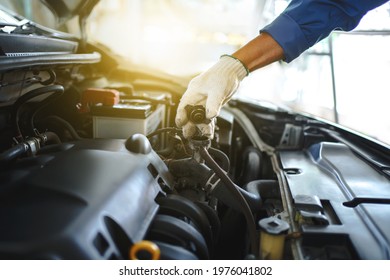 Young auto mechanic checks the water level in the radiator in the car. He was wearing white cloth gloves, holding the radiator cap. - Shutterstock ID 1976041802