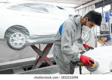 Young Auto Mechanic Man Buffing And Polishing Car Holding Polisher In Hand, In Repair Shop. Renew Service Station Shop By Power Buffer Machine