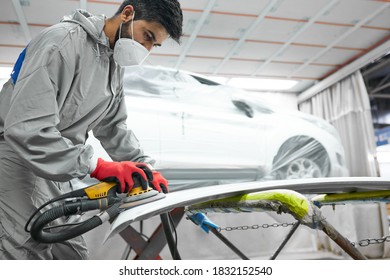 Young Auto Mechanic Man Buffing And Polishing Car Holding Polisher In Hand, In Repair Shop. Renew Service Station Shop By Power Buffer Machine