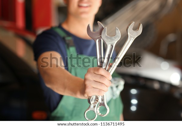 Young auto
mechanic with tools in car service
center