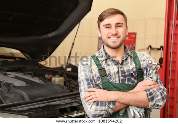 Young\
auto mechanic with tools near car in service\
center