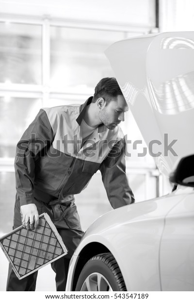 Young automobile mechanic examining car in\
automobile shop