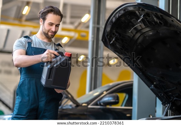 Young automotive technician performing the engine\
oil change