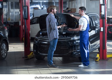 Young Automotive Technician Talking With Male Client