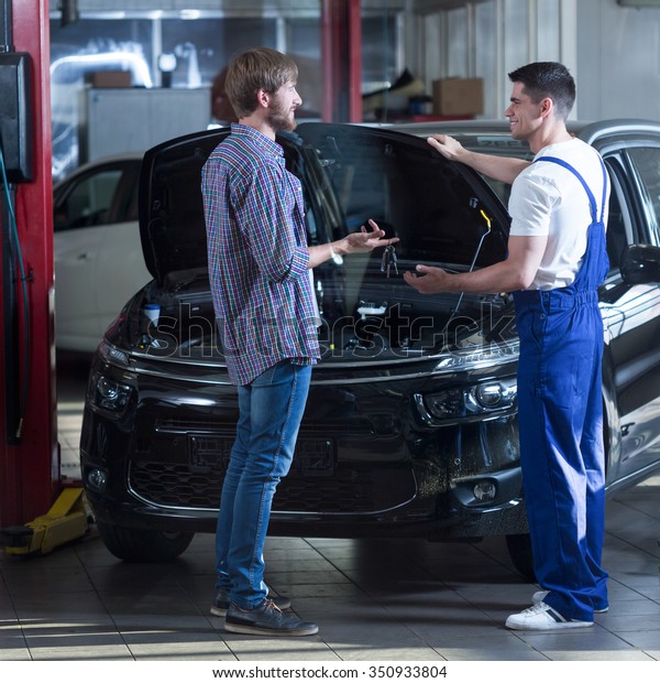 Young
automotive technician talking with male
client