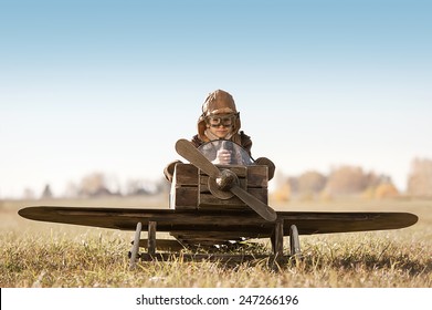 Young Aviator sits in his makeshift toy airplane on airport parking
