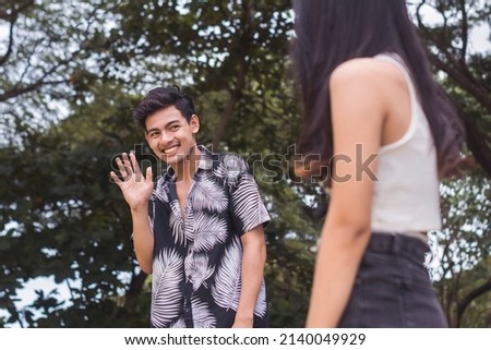 A young awkward man saying hi to his crush. Attracted to a woman outside the park. Being shy about his personality and looks. Foto d'archivio © 