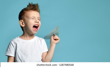 Young Baby Boy Kid In White T-shirt Hold Paper Plane Origami Shouting Screaming On Blue Green Mint Background 