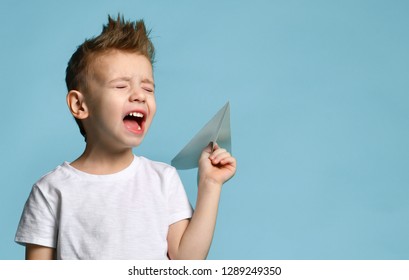 Young Baby Boy Kid In White T-shirt Hold Paper Plane Origami Shouting Screaming On Blue Green Mint Background 