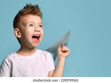 Young Baby Boy Kid In White T-shirt Hold Paper Plane Origami Shouting Screaming With Open Mouth On Blue Green Mint Background 