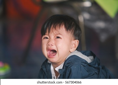 A Young Baby Having A Fit On The Ground Crying And Making A Pout Face.