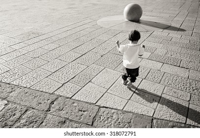 Young Baby Running Towards Stone Ball, Black And White And Copy Space