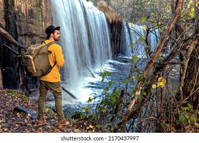 young backpacker looking at the waterfall in the forest